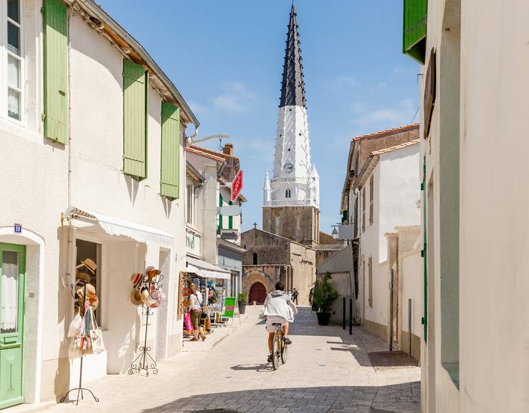 Ruelle avec cycliste et clocher à Saint-Martin-de-Ré.
