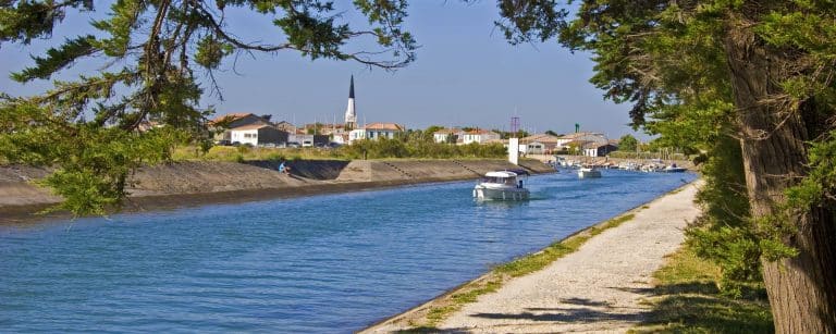Canal avec bateaux et maisons sous ciel bleu.