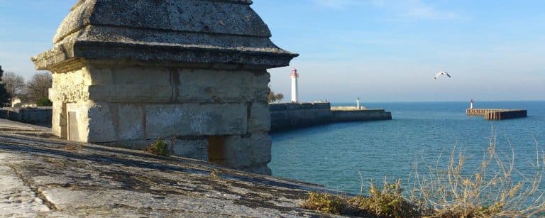 Phare sur la côte avec mer et ciel bleu.