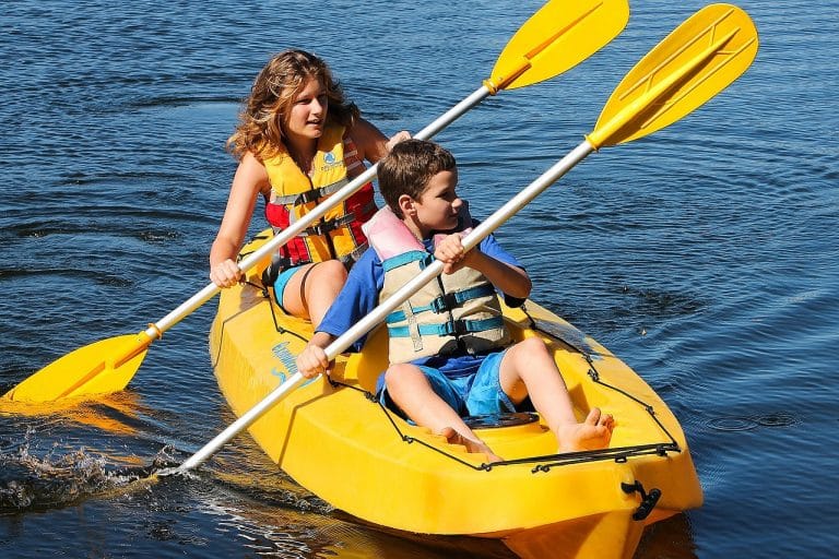 Enfants pagayant en kayak jaune sur l'eau.