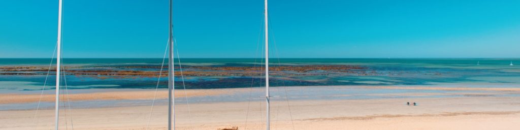 Plage avec mer turquoise et voiliers.